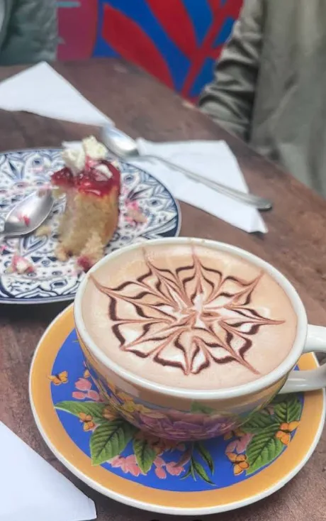 Capuchino con arte latte de estrella junto a un trozo de torta