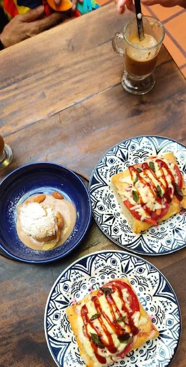 Mesa con focaccias gratinadas, un postre con helado y un café con espuma