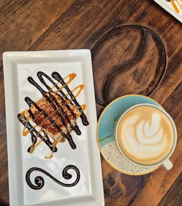Postre con salsas de chocolate y caramelo junto a un latte